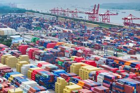 Des piles de conteneurs d'expédition de différentes couleurs sont visibles dans un port en Chine.