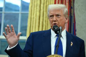 Donald Trump parlant sur un podium dans une pièce avec une fenêtre et des rideaux visibles en arrière-plan