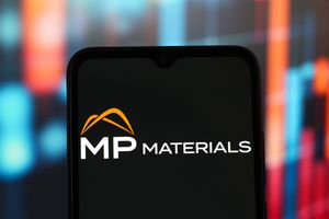 Le logo MP Materials sur un écran de smartphone, avec un fond bleu et orange