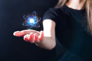 Une personne tenant dans sa main un hologramme d'atome brillant, symbolique des concepts scientifiques