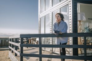 Une femme s’appuie sur la balustrade d’un balcon.