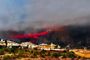 Des maisons menacées par un incendie de forêt en arrière-plan
