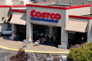Vue aérienne d'un magasin Costco, montrant le logo Costco et les clients sortant du bâtiment avec des caddies.
