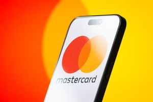 Le logo Mastercard est affiché sur l'écran d'un smartphone, avec les cercles rouges et jaunes superposés emblématiques de l'entreprise visibles en arrière-plan.