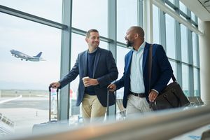 Voyage d'affaires, équipe à l'aéroport et hommes, prendre un vol pour un voyage de travail avec conférence ou séminaire de formation avec comptable. Marchez, parlez et diversité avec la convention financière et le partenariat