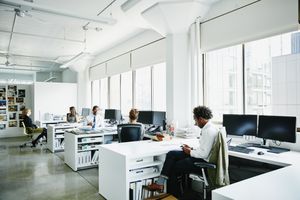 Environnement de bureau avec des personnes travaillant à des bureaux ouverts avec de grandes fenêtres