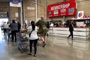 Plusieurs clients avec des caddies chez Costco près de la sortie et du bureau des membres.